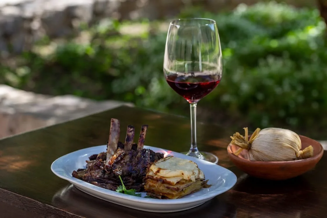 Plato de cordero con pastel de papa y copa de vino tinto en Calandria