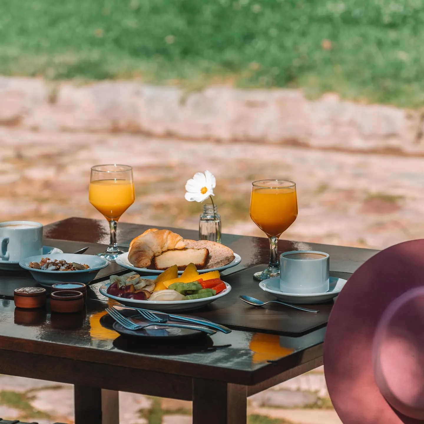Desayuno servido al sol, con jugo de naranja, frutas y café