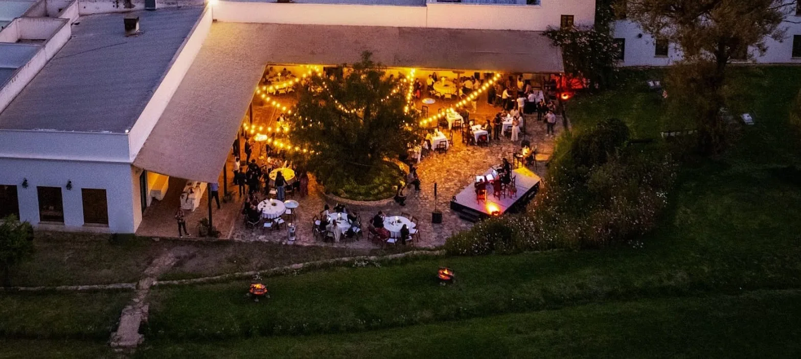Vista aérea nocturna de una fiesta en la galería del hotel, iluminada con guirnaldas de luces