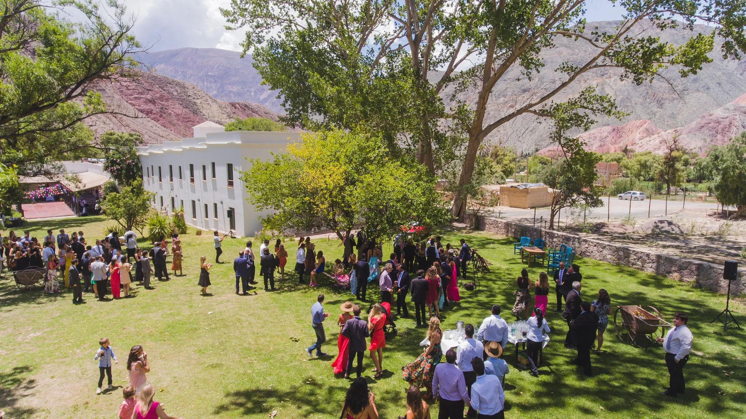 Invitados de una boda reunidos en el parque, con la casona y los cerros de fondo