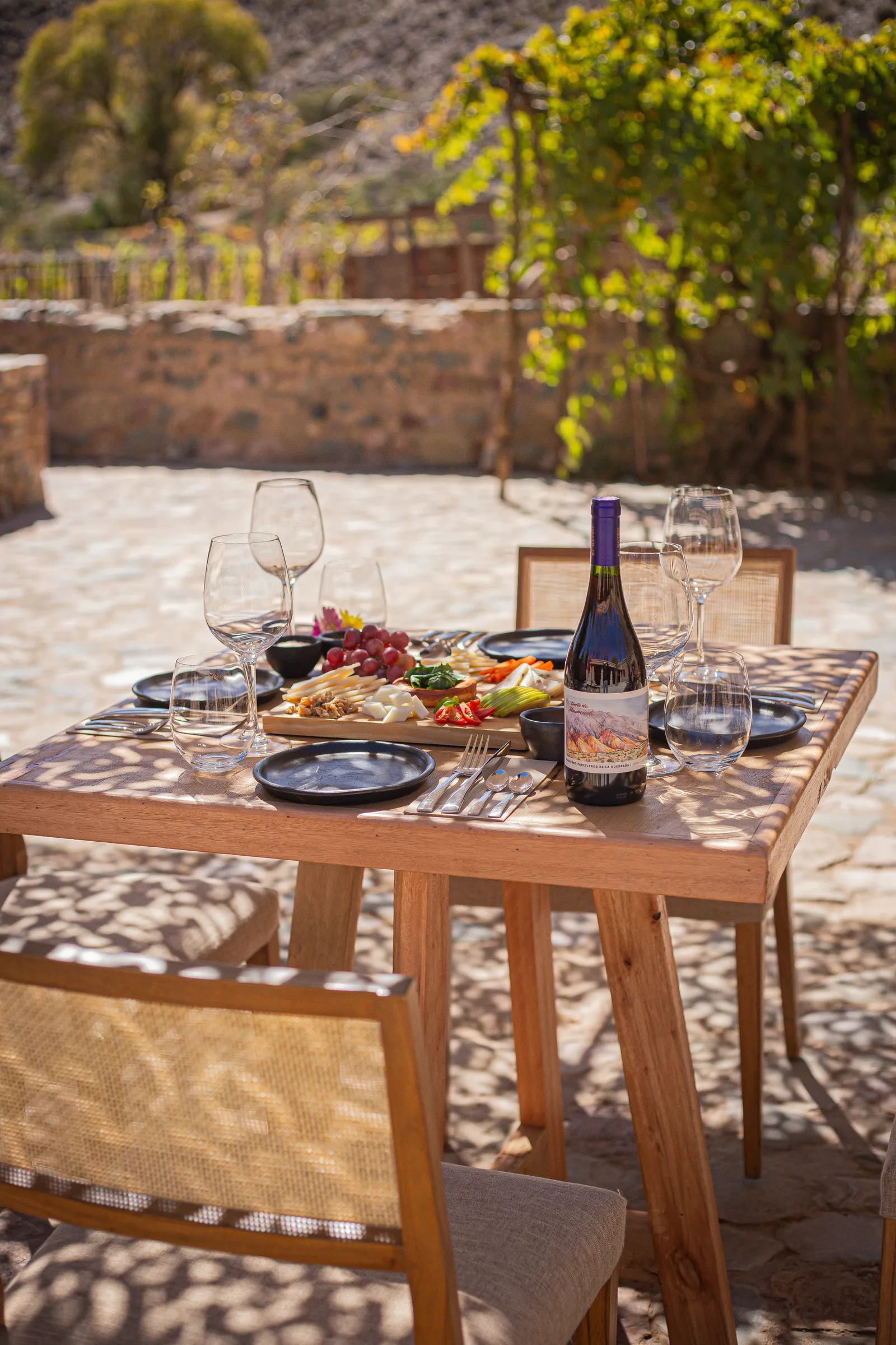Mesa servida con picada y vino en el patio de piedra de la Casa Boutique