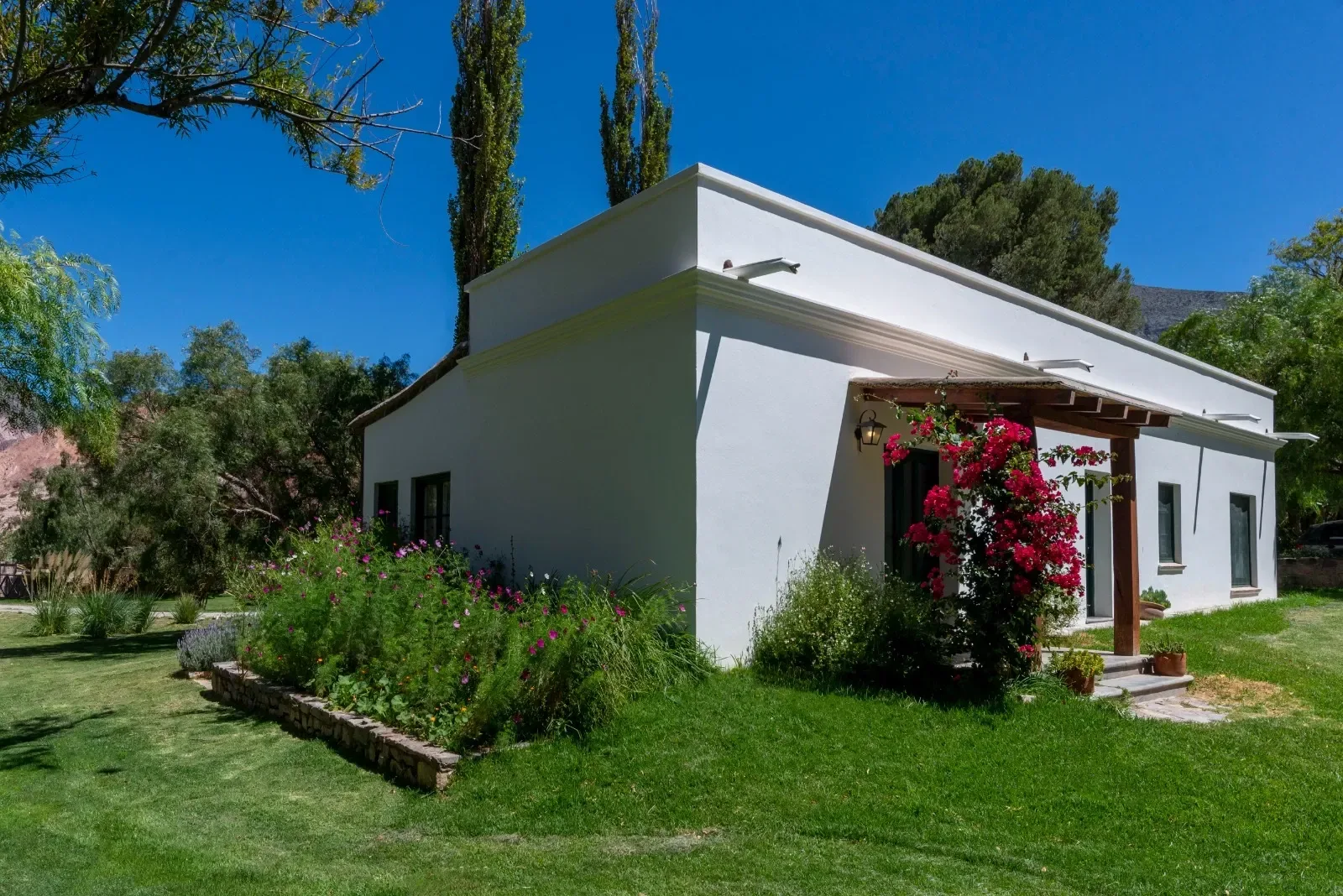 La Casa Boutique, de muros blancos, con santa rita en flor sobre la galería