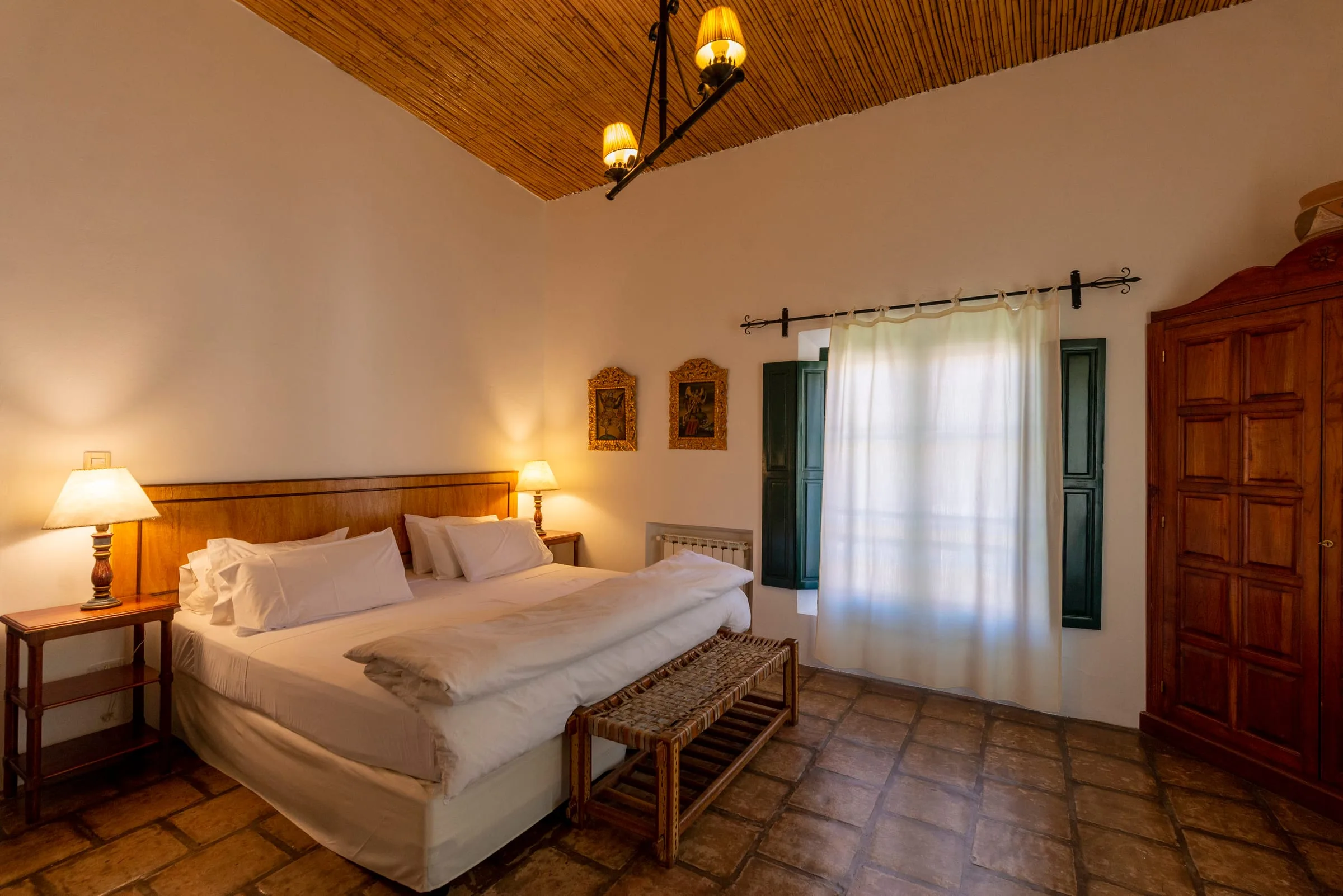 Suite con techo de madera a dos aguas, cama king y veladores encendidos