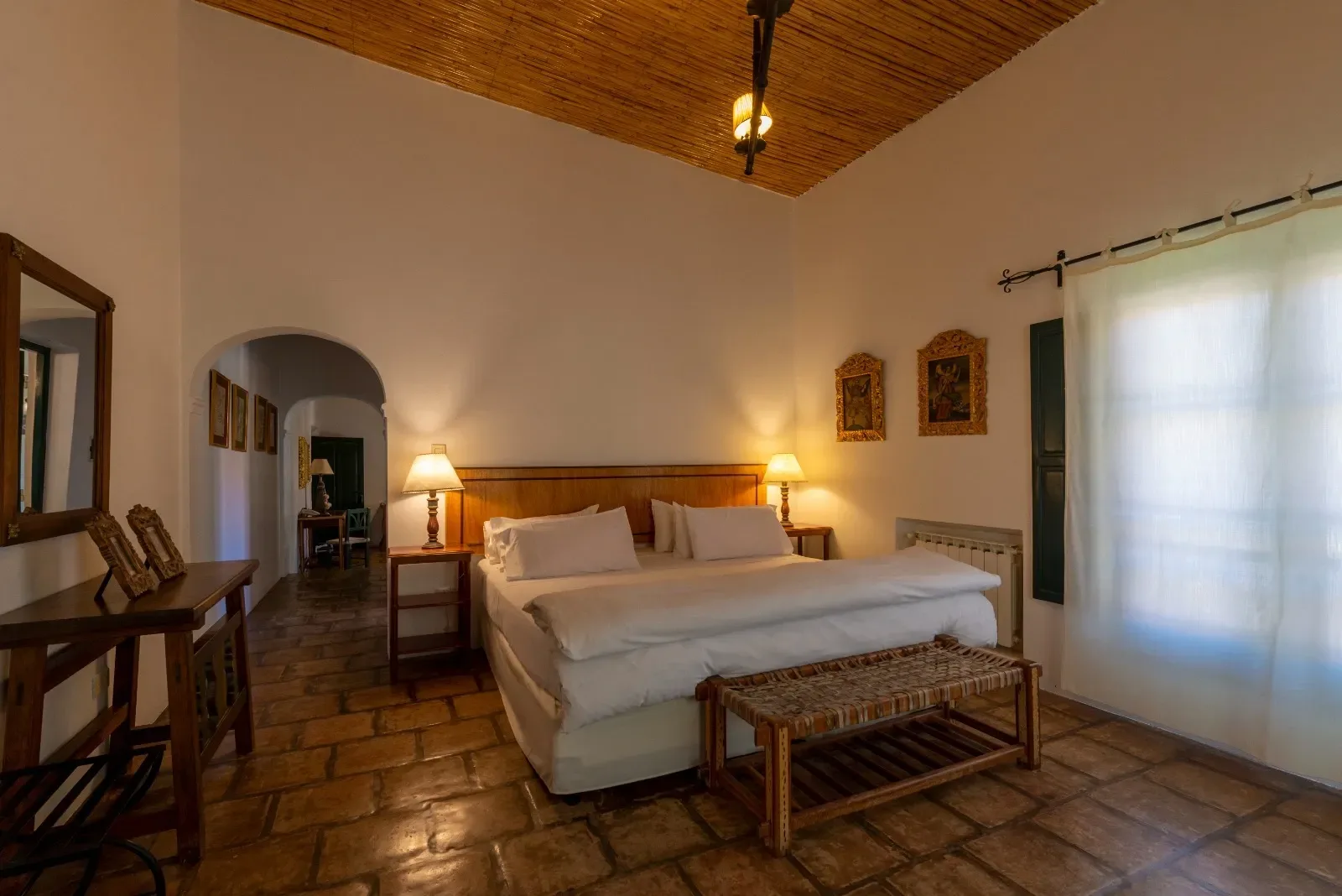 Dormitorio de la suite con arco de paso y cuadros coloniales
